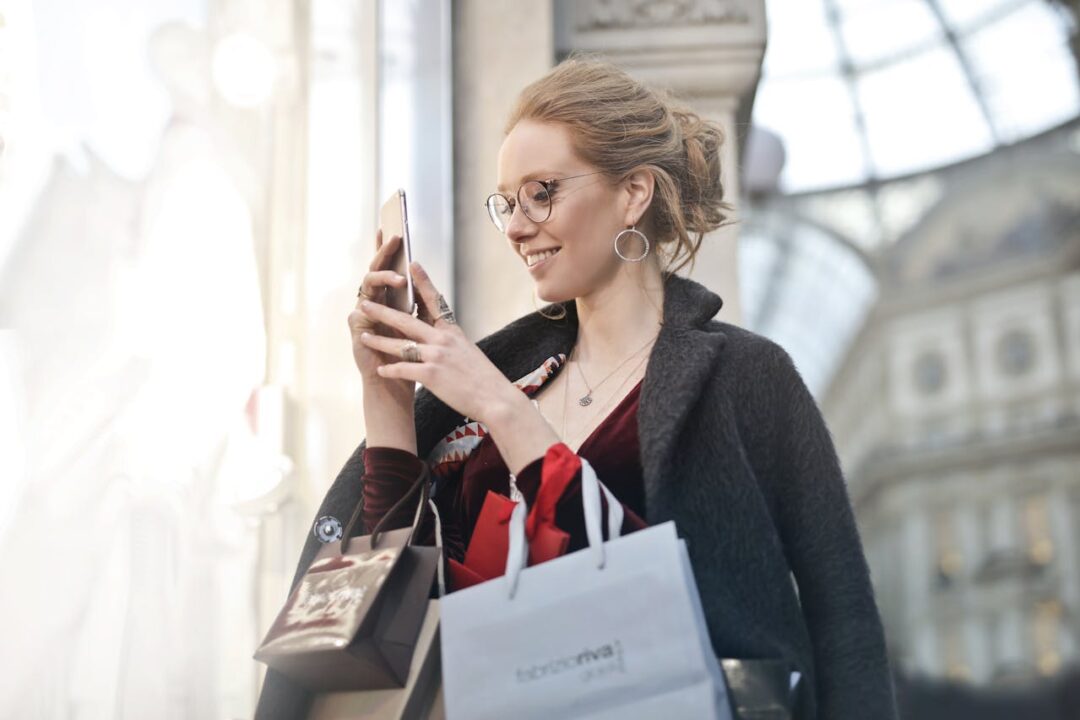  a woman with shopping bags, checking her email